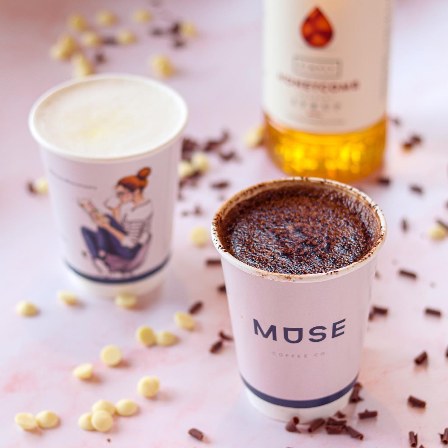 Coffee machine pouring coffee into two branded paper cups.