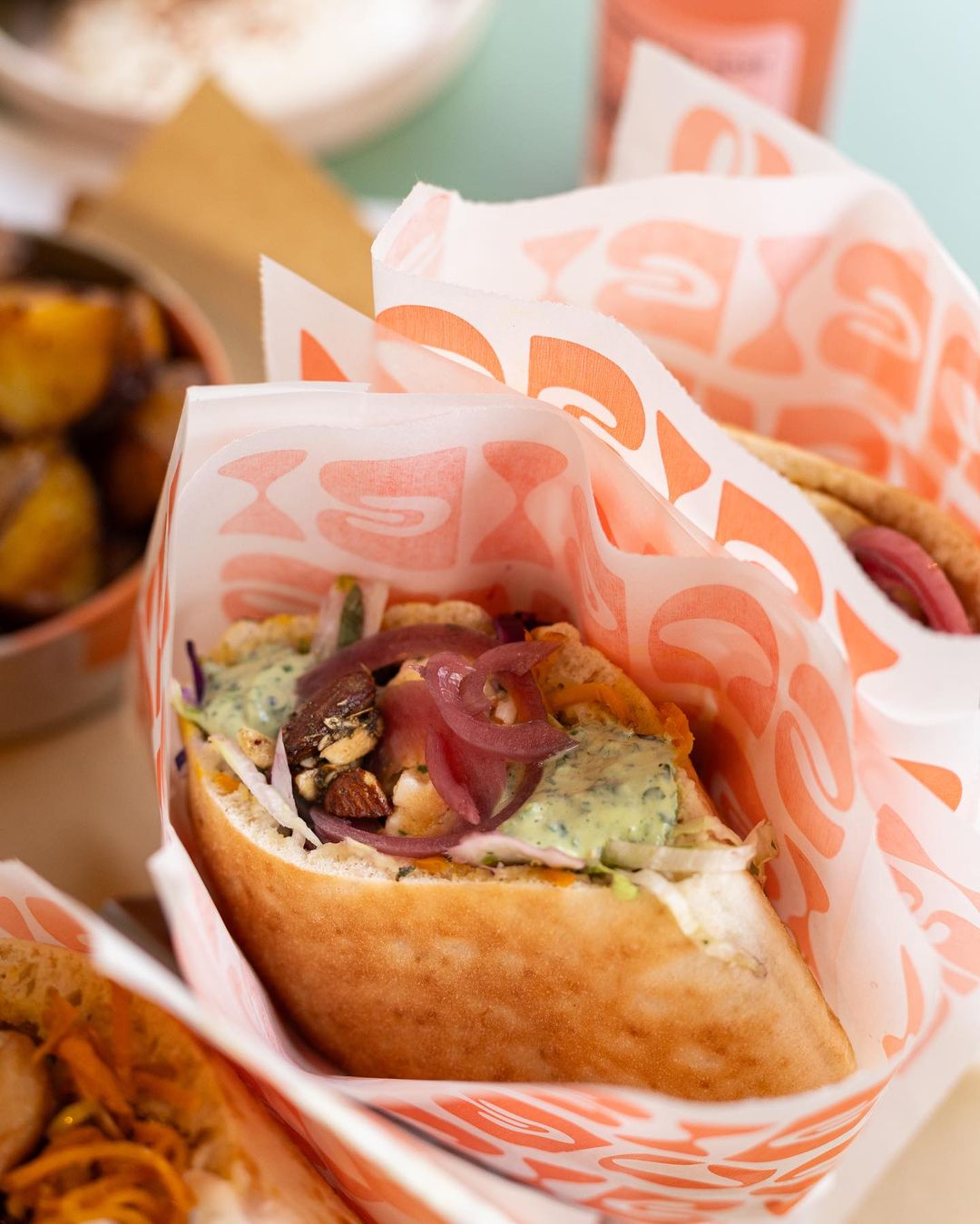 Close-up of a pita wrapped in branded greaseproof paper, perfect for takeaway